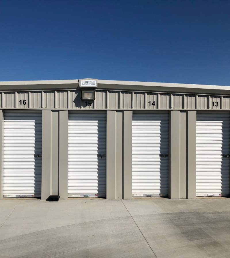 A front-facing view of numbered, secure self-storage units with white metal doors and outdoor facility lighting for enhanced safety and visibility.