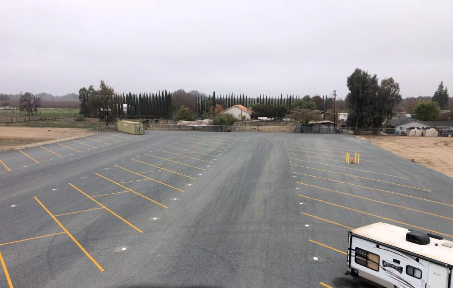 A secure, high black metal fence with curved top pickets bordering a landscape of smooth river rocks and gravel, protecting the storage facility interior.